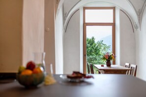 A dining table with a bowl of fruit, a glass of water, and a vase of flowers. - Apartment 'Ansitz Baumannhof 1818' with Mountain View, Shared Garden and Wi-Fi (Pfalzen)