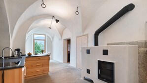 Een keuken met een centraal eiland, een inbouwoven en een uitzicht door een boogvormige doorgang.
