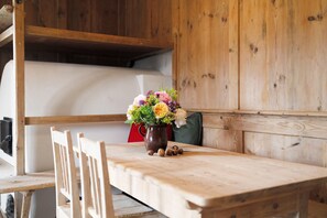 Ein Holztisch mit einer Blumenvase, ein Stuhl und ein Etagenbett im Hintergrund.