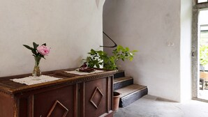A wooden desk with a vase of flowers, a potted plant, and a small decorative item.