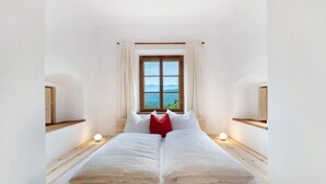 A room with a bed, a window with curtains, and a view of the outdoors.