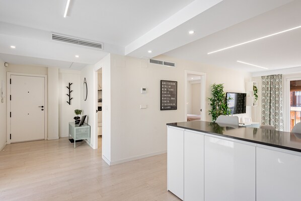 A modern kitchen with white cabinetry, a black countertop, and a built-in stove.