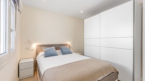 Un dormitorio con cama, mesitas de noche, un armario y una ventana.