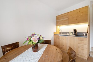 A wooden dining table with a lace tablecloth, a vase of flowers, and wooden chairs.