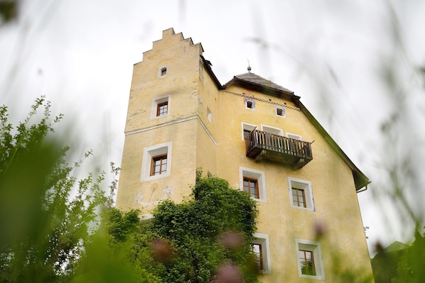 A historic building with a tower, multiple windows, and a balcony.