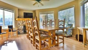 A dining area with wooden chairs and a table, a ceiling fan, and large windows with blinds. - Large 2 bedroom at Riverside / Great Location (Fernie)
