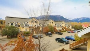 A residential area with houses, a parking lot, and mountains in the background. - Large 2 bedroom at Riverside / Great Location (Fernie)