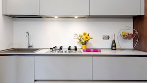A kitchen with a sink, stove, and a flower vase. - Apartment 'La Sartoria' with Dedicated Parking and Air Conditioning (Porlezza)