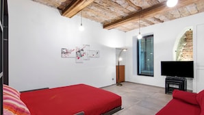A room with two beds, a TV, a fireplace, and artwork on the wall. - Apartment 'La Sartoria' with Dedicated Parking and Air Conditioning (Porlezza)