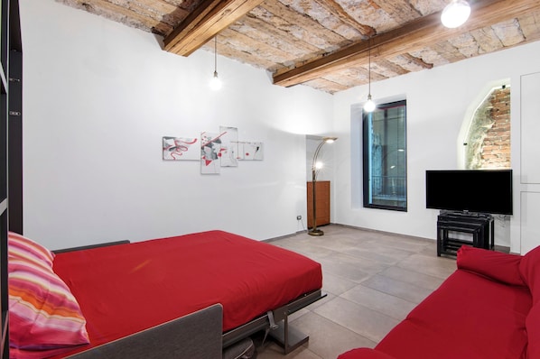 Une chambre avec deux lits, une télévision, une cheminée et des œuvres d’art accrochées au mur.