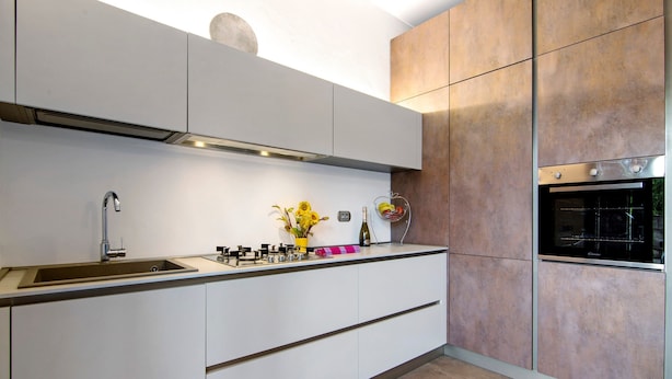 A modern kitchen with a built-in oven, a sink, and a countertop with a vase of flowers. - Apartment 'La Sartoria' with Dedicated Parking and Air Conditioning (Porlezza)