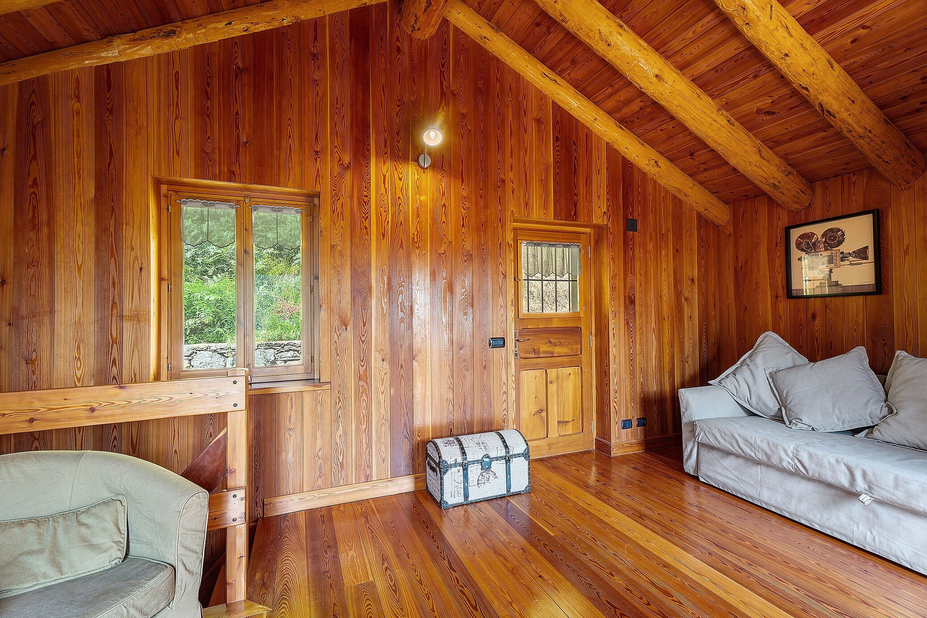 L’intérieur d’un chalet en bois, avec un canapé, une malle et une porte.