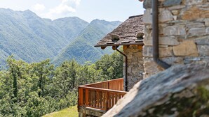 A stone building with a wooden balcony overlooking a mountainous landscape. - Exclusive Chalet 'La Libellula' with Stunning Mountain Views (Scopello)