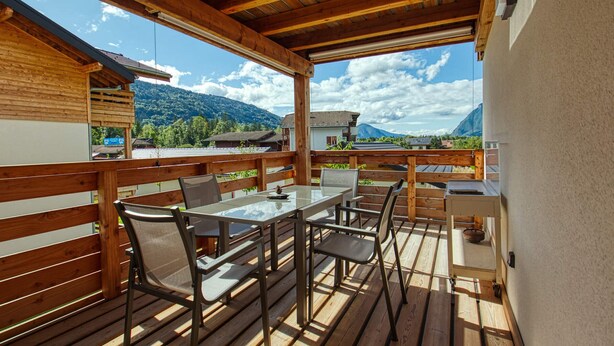 A wooden deck with a table and chairs, overlooking a mountainous landscape. - Bright apartment in Verchaix, 4 pers, terrace, garage, Wifi (Verchaix)