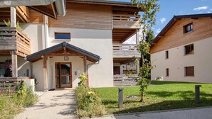 A modern building with a wooden facade, a covered entrance, and a well-maintained lawn. - Bright apartment in Verchaix, 4 pers, terrace, garage, Wifi (Verchaix)