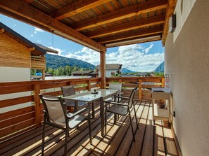 A wooden deck with a table and chairs, overlooking a mountainous landscape. - Bright apartment in Verchaix, 4 pers, terrace, garage, Wifi (Verchaix)