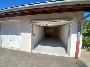 A garage with a concrete floor, a white door, and a wooden ceiling. - Bright apartment in Verchaix, 4 pers, terrace, garage, Wifi (Verchaix)