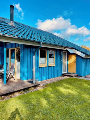 A blue building with a tiled roof, a covered porch, and a grassy yard. - Premium-ferienhaus im Extertal Ferienpark - Wandern, Natur, Wald, Sauna # (Extertal)