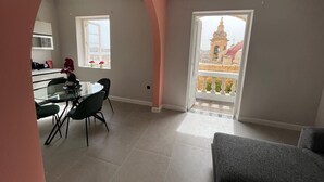 A modern living room with a dining area, a balcony with a view of a building, and a kitchen in the background. - Valletta heart, 3-room superior apartment (Valletta)