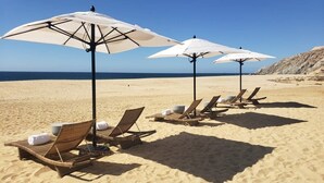 A beach with sun loungers and white umbrellas.