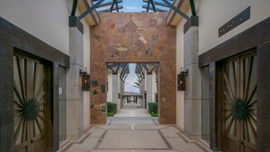 A corridor with stone walls and wooden doors, leading to a reception area. - Quivira Ocean view private villa with pool (Cabo San Lucas)