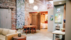 A cozy room with a brick wall, a wooden dining table, and a bed.