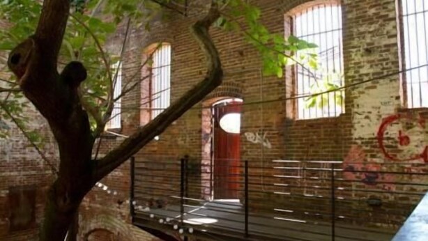 An interior with brick walls, arched windows, and a staircase.