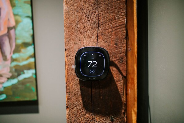 A thermostat mounted on a wooden surface, displaying a temperature of 72 degrees.