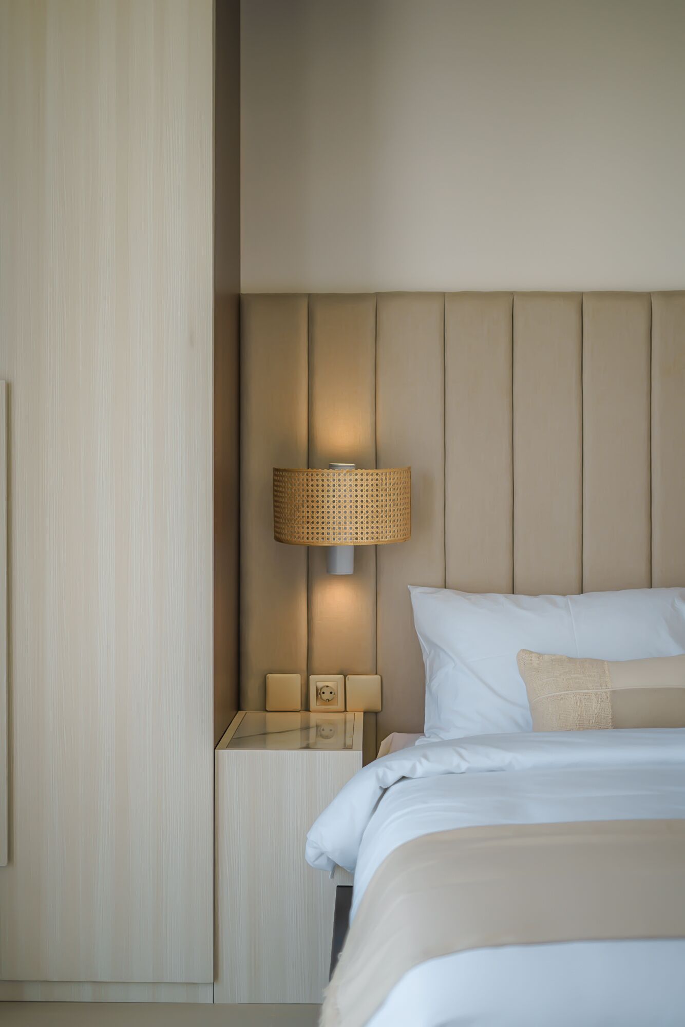 Une chambre d’hôtel bien rangée, avec un lit, une table de chevet, une lampe et une armoire.