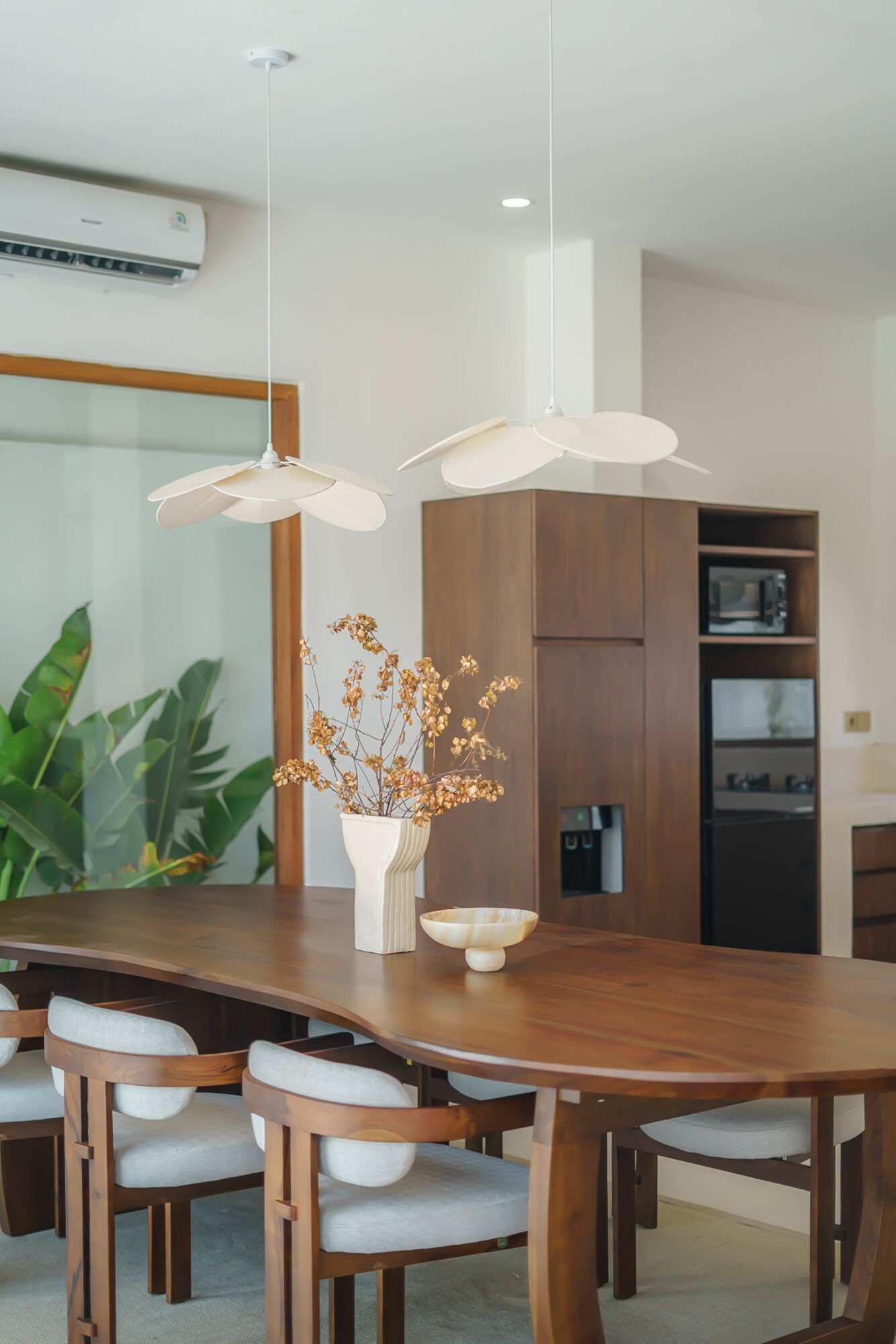 Un comedor moderno con una mesa de madera, sillas blancas y lámparas colgantes.