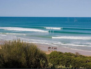 A beach with waves and a group of people on horseback.