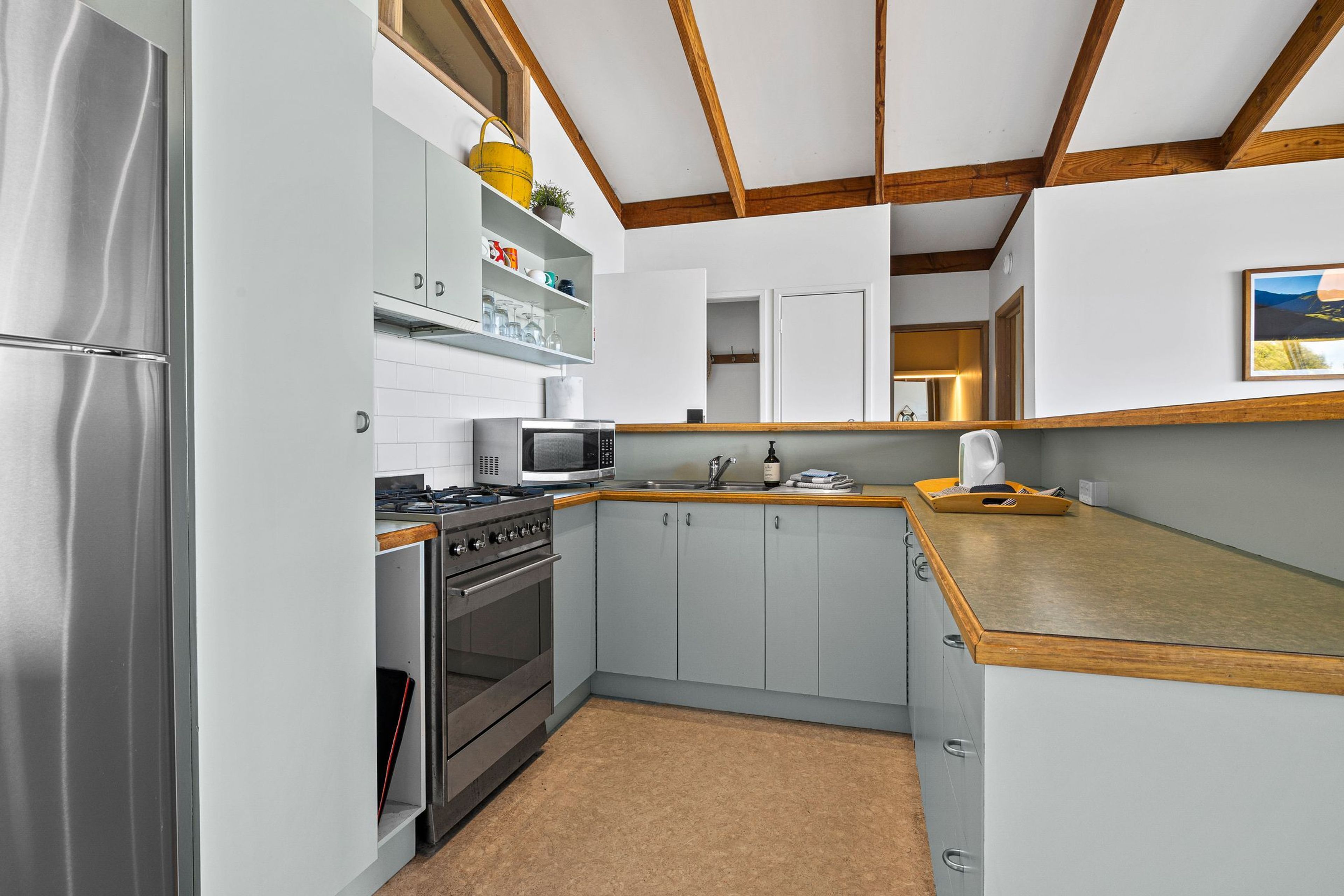 Eine kleine Küche mit einem Edelstahl-Kühlschrank, einer Mikrowelle, einem Backofen und einem Spülbecken.
