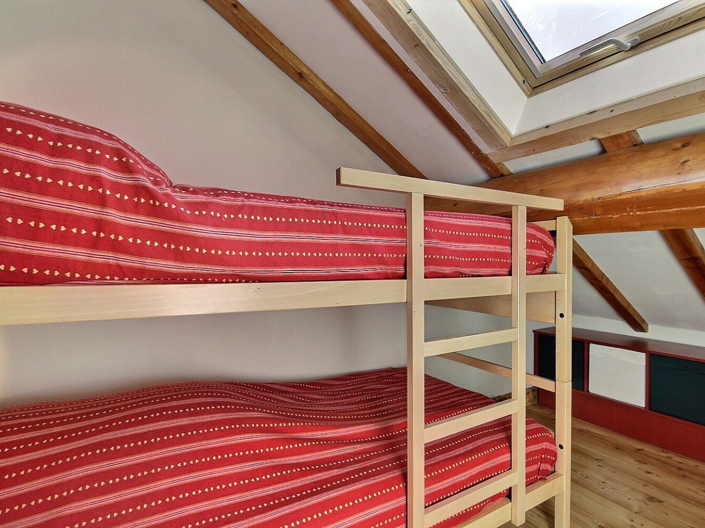 A dormitory room with bunk beds and a skylight.