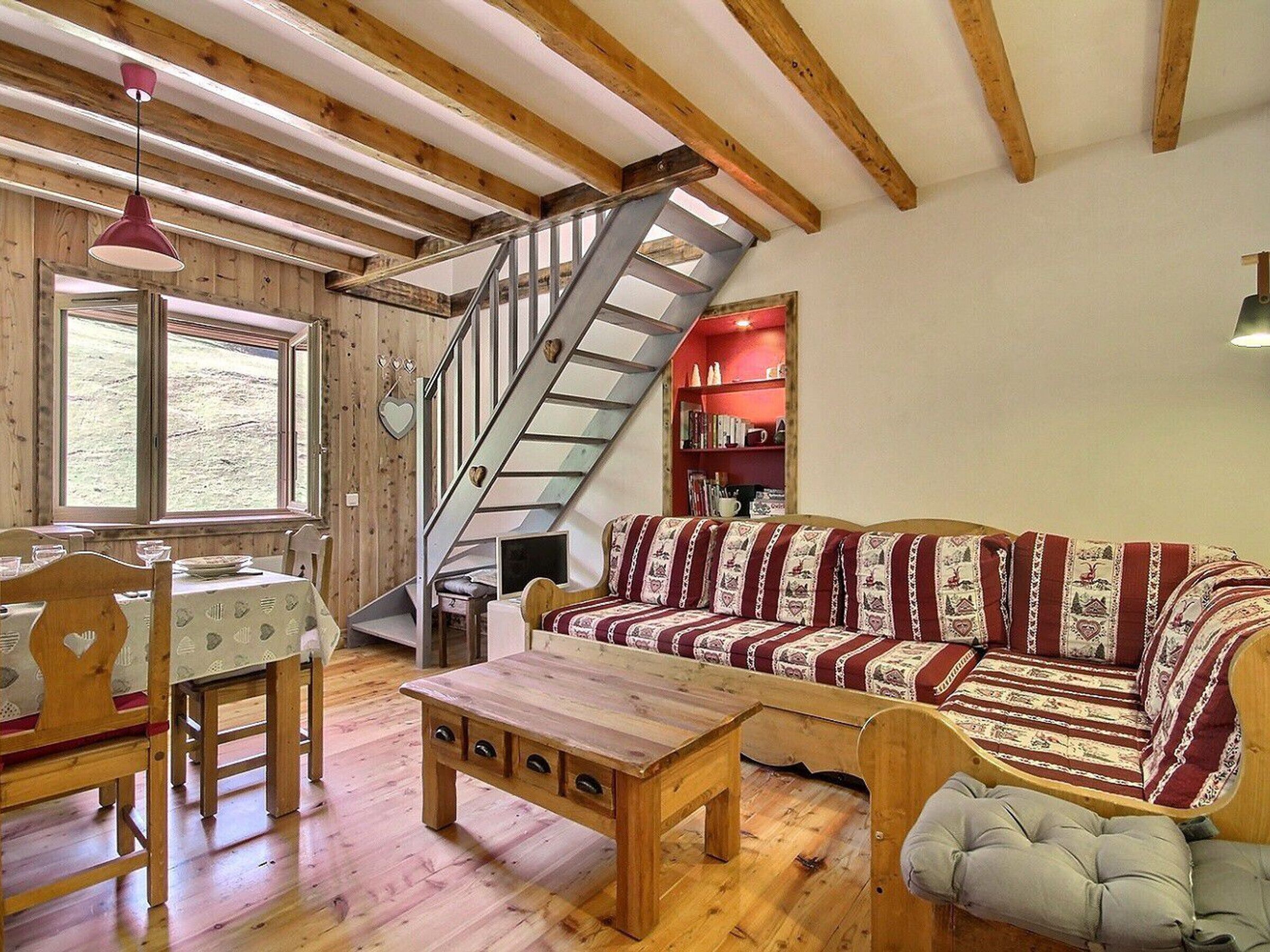 A cozy living room with a wooden staircase, a sofa, a table, and a bookshelf.