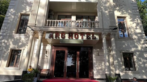 Un bâtiment doté d’une entrée imposante, d’un tapis rouge et de l’enseigne « ARG HOTEL » au-dessus des portes.