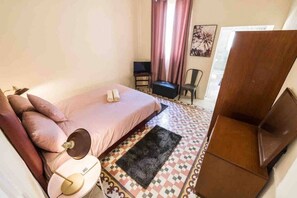 Un dormitorio pequeño y acogedor con una cama individual, una silla, un escritorio y un armario.