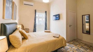 Ein Schlafzimmer mit einem Bett, einem Fernseher, einer Klimaanlage und einem gemusterten Boden.