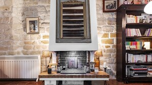 A cozy room with a fireplace, a bookshelf, and a stone wall.