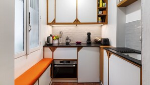 A compact kitchen with white cabinets, a black countertop, and a small oven.