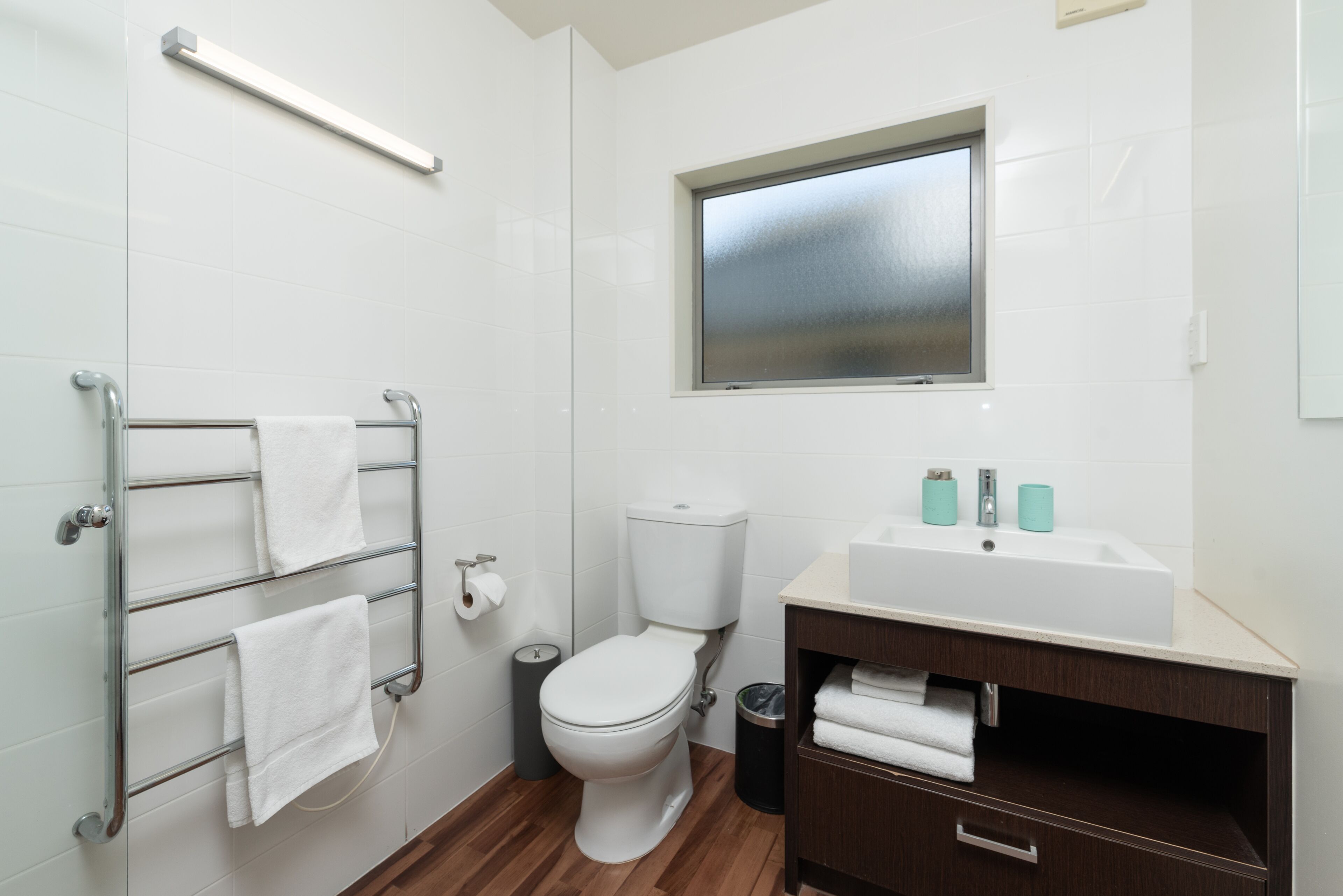 Une salle de bain moderne équipée de toilettes, d’un lavabo et d’un porte-serviettes.