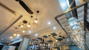 Un intérieur moderne agrémenté de ventilateurs de plafond, de luminaires suspendus et de bouteilles de vin exposées sur des étagères.