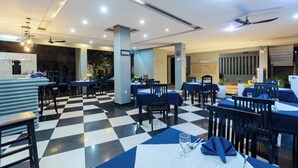 Un restaurant avec un sol à carreaux, des tables recouvertes de nappes bleues et des ventilateurs de plafond.