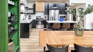 A modern kitchen with a central island, black cabinets, stainless steel appliances, and a green storage unit. - Heated Private Pool, Lake view, No steps | Mini Thistle (Hollister)