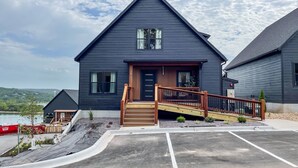 A two-story house with a dark exterior, a front porch with wooden steps, and a small deck. - Heated Private Pool, Lake view, No steps | Mini Thistle (Hollister)