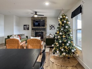 A living room with a fireplace, a Christmas tree, and a dining area. - Private hot tub, Pool table, Dog-friendly | Mini Wildflower (Hollister)
