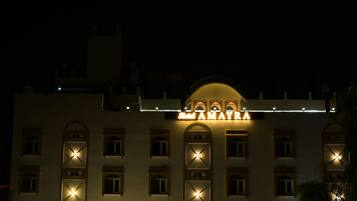Hotel com uma entrada em arco imponente, várias varandas e fachada bem iluminada.