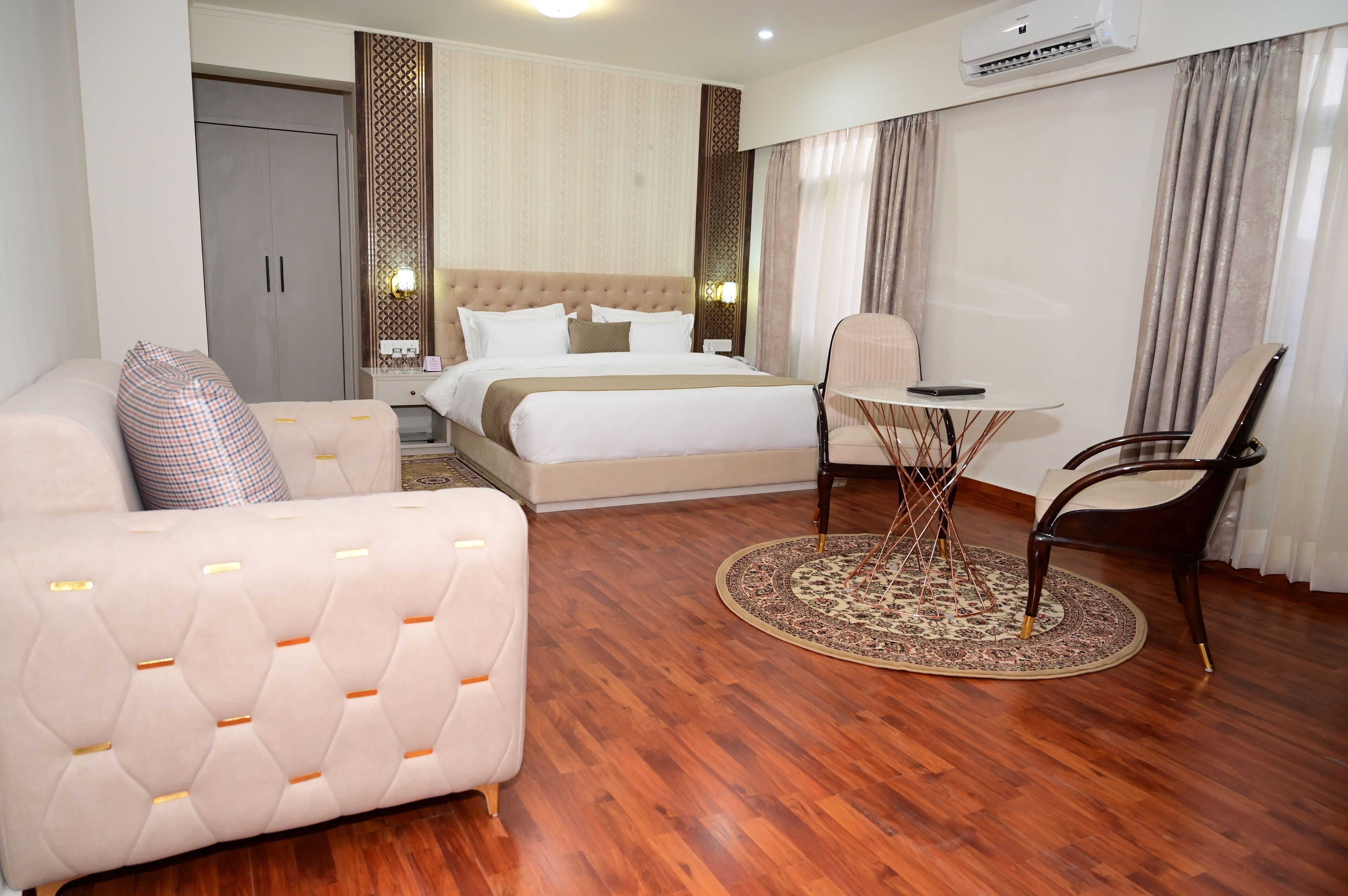 Une chambre d’hôtel avec un lit, un canapé, une table ronde et une chaise.