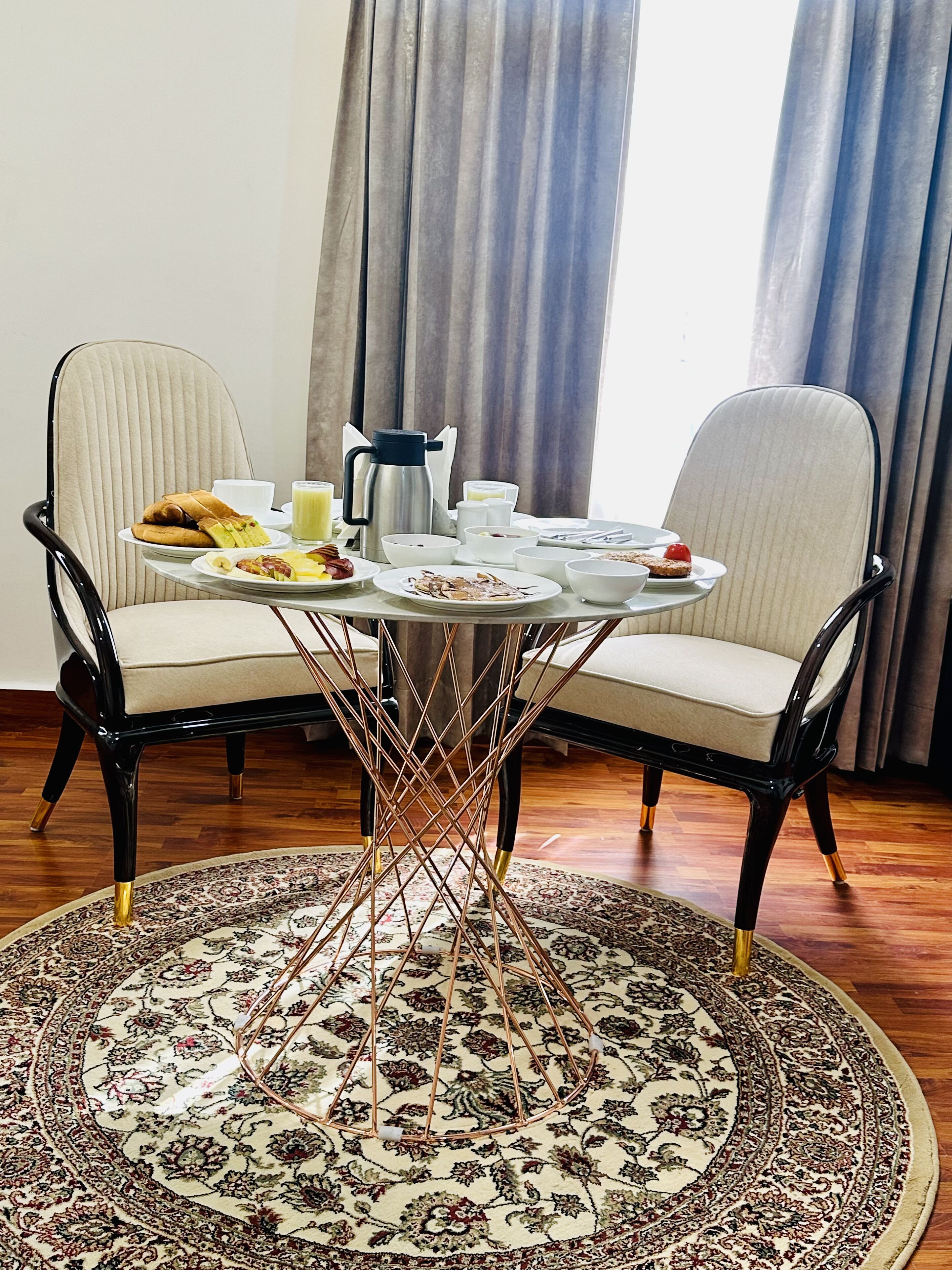 Un comedor con dos sillas, una mesa redonda y un tapete estampado.
