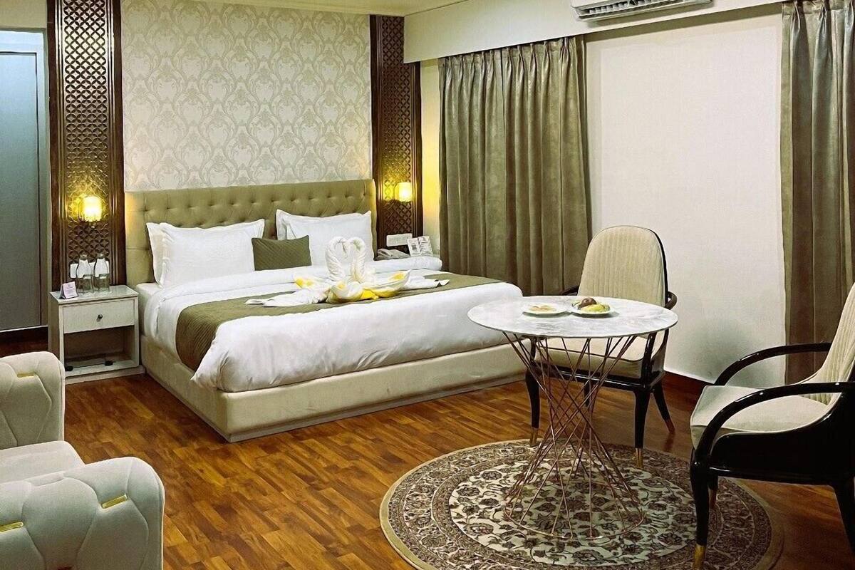 Een hotelkamer met een groot bed, een ronde tafel met stoelen, een plafondventilator en een airconditioning.