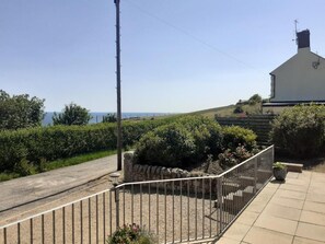 Stunning coastal residence with a pitched roof and chimney, surrounded by lush gardens and a clear sea view.